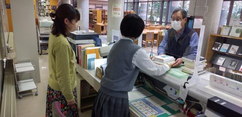 図書館カウンターでの書籍貸し出しの様子（中央がインターンシップ生）